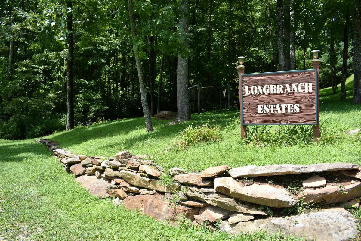 Wooden Long Branch Estates entrance sign surrounded by trees